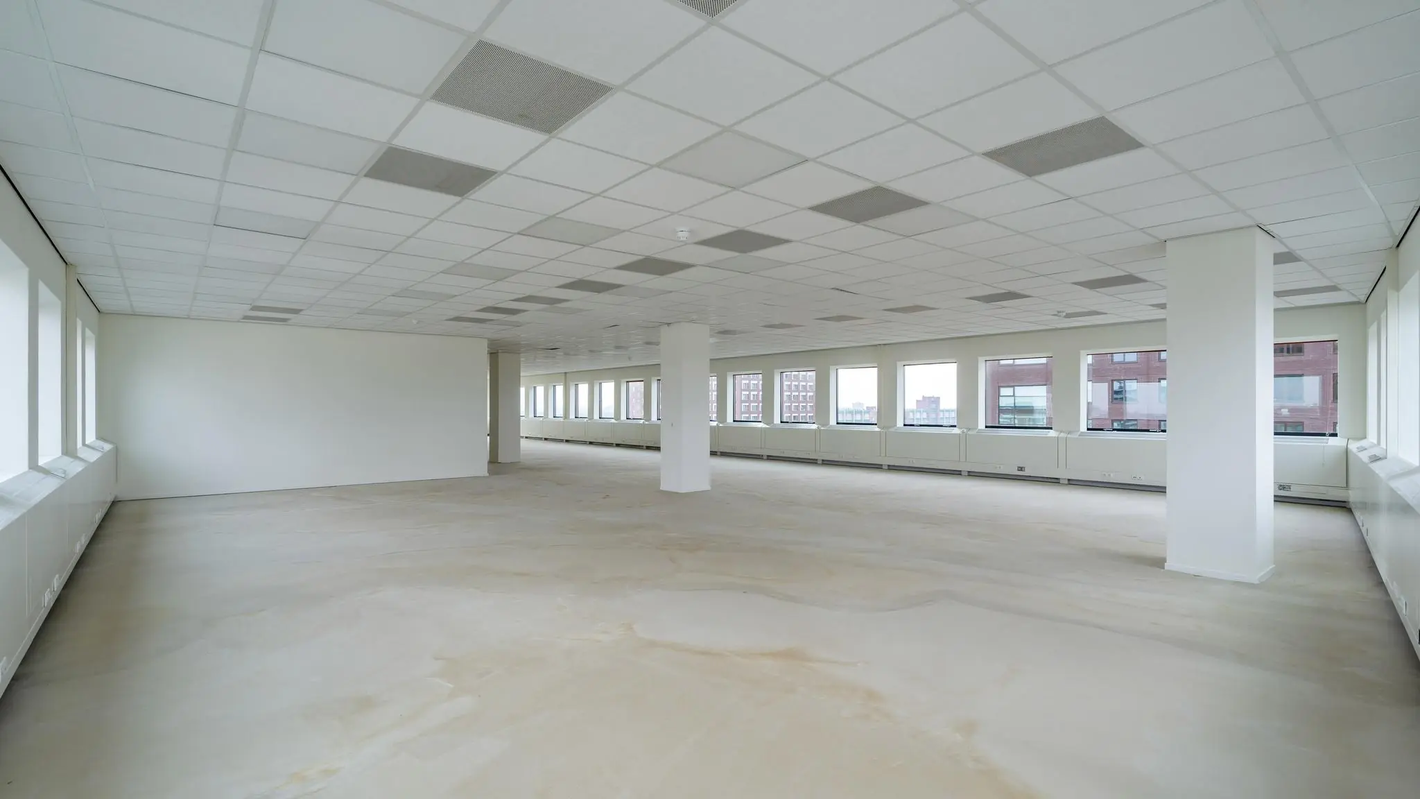 Leeg kantoorpand met systeemplafond en grote ramen aan het Johanna Westerdijkplein.